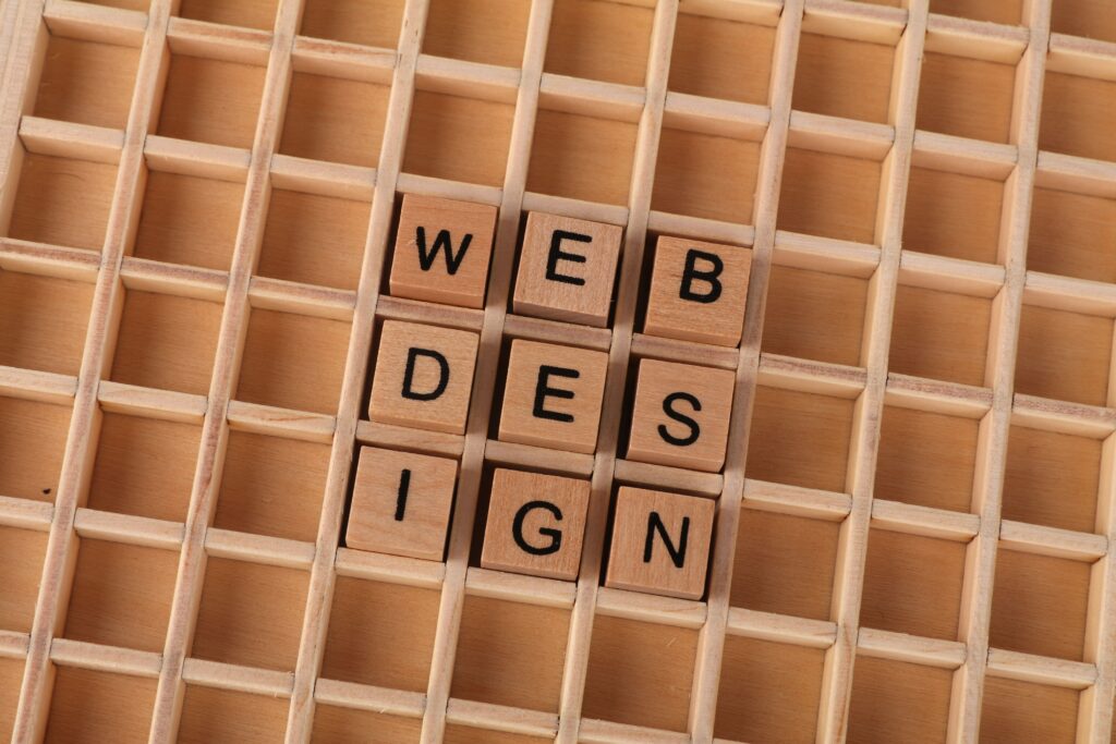 Wooden letter tiles spelling Web Design on a grid background.